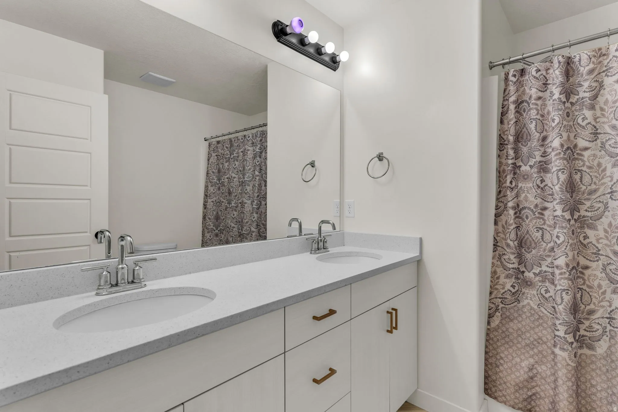 Double vanity with integrated sinks, light-toned countertops, and brushed nickel faucets