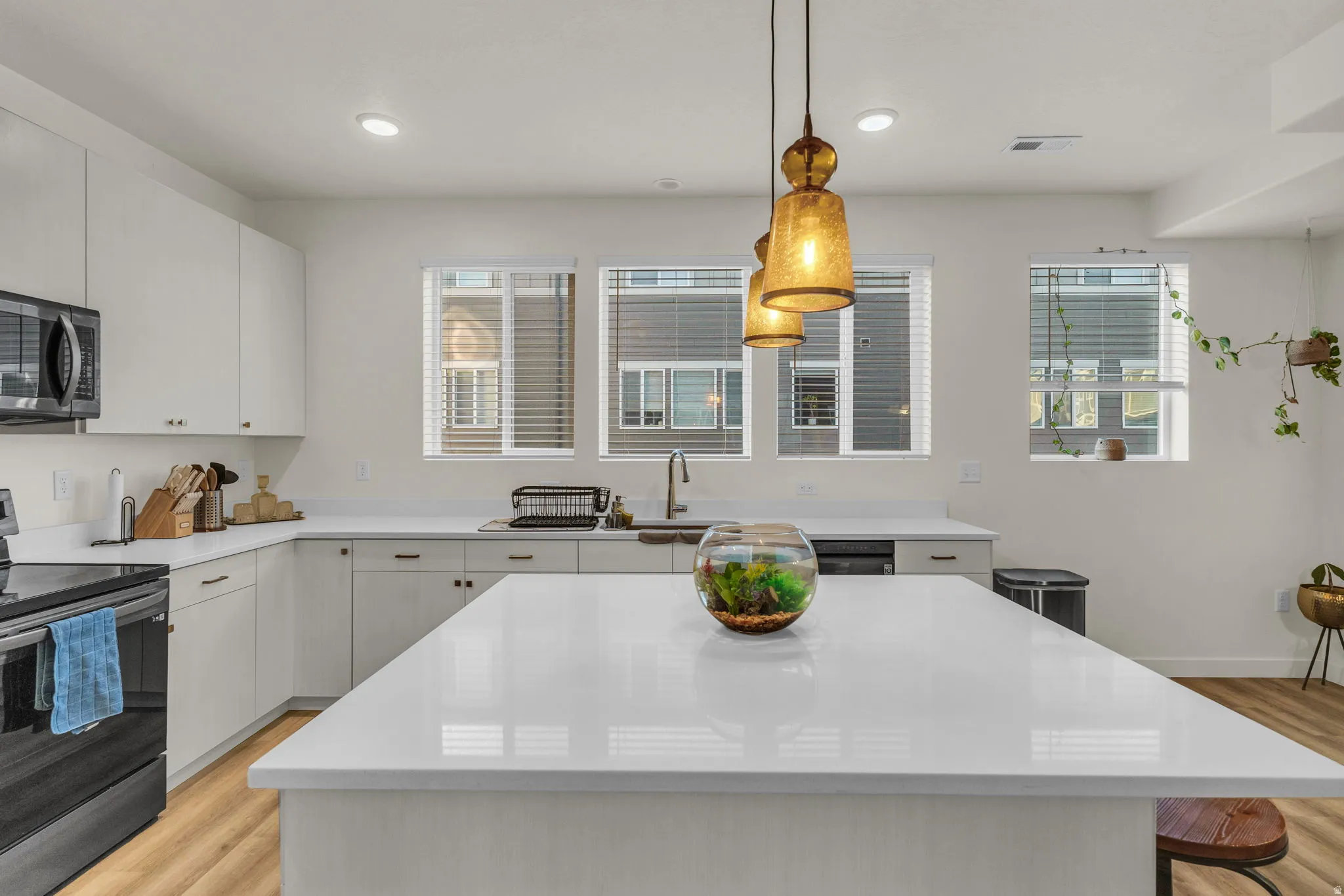 White flat-panel cabinetry with light-toned countertops, a central island, and multiple windows