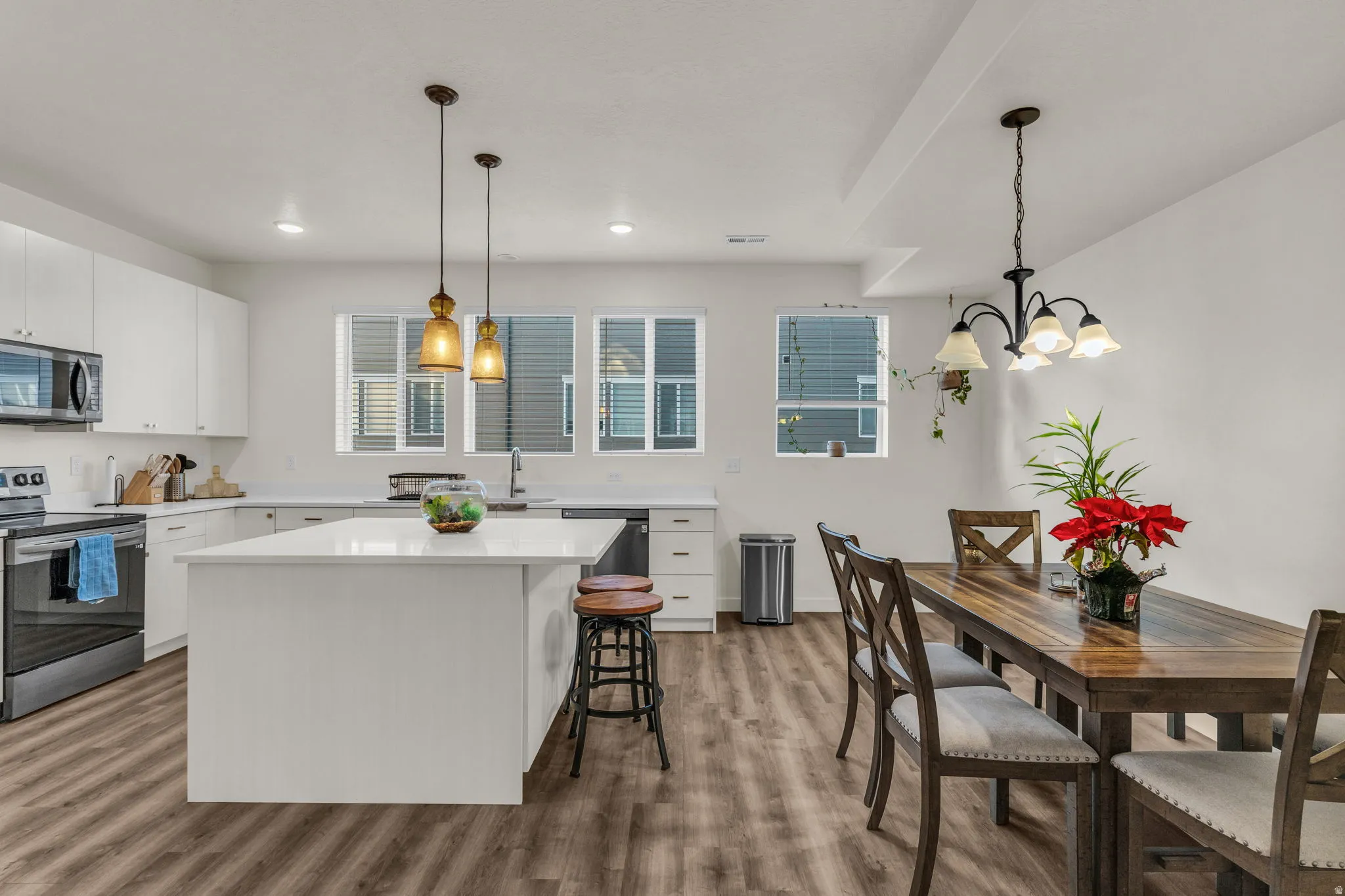Modern kitchen featuring white cabinetry, stainless steel appliances, a center island with countertop seating, and wood-finish flooring