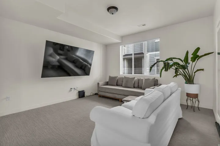 Recessed lighting and a wall-mounted television against a neutral wall