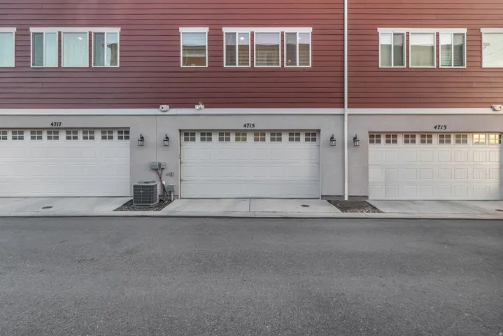 Red horizontal siding, white panel garage doors, concrete driveways, and exterior wall lanterns