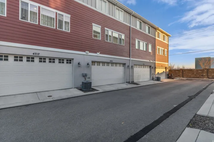 Multi-level structure featuring red horizontal siding, multiple white-framed windows, and white garage doors with window inserts