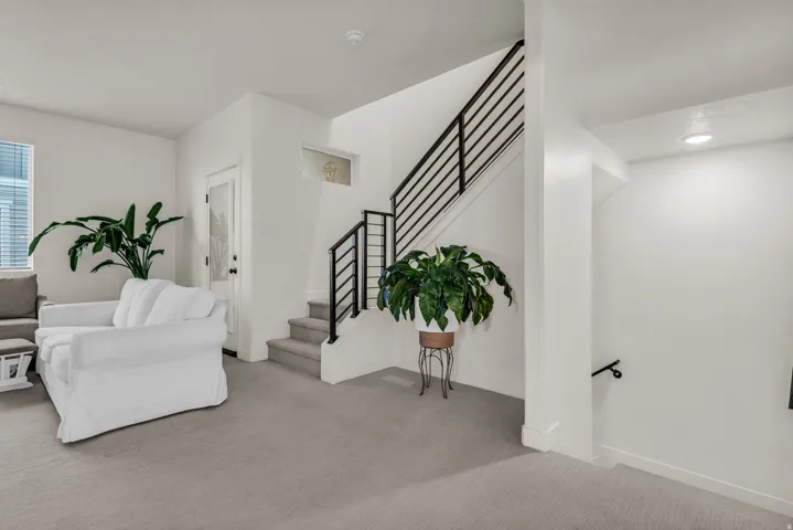Carpeted flooring throughout, staircase with modern black railings, recessed ceiling lighting, and a transom window