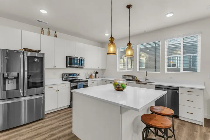 Kitchen featuring stainless steel appliances, white cabinetry, a central island with countertop, recessed lighting, and wood-finish flooring