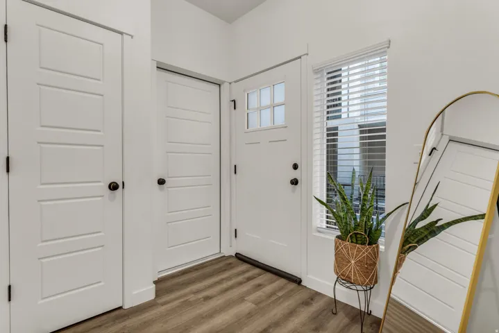 Wood-finish flooring, white panel doors, and a front entry door with a frosted glass insert