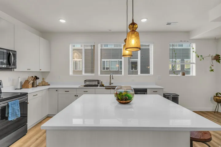 White flat-panel cabinetry with light-toned countertops, a central island, and multiple windows
