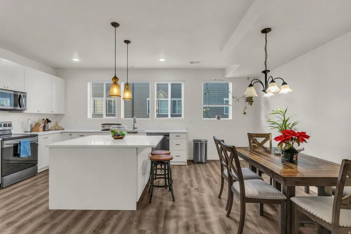 Modern kitchen featuring white cabinetry, stainless steel appliances, a center island with countertop seating, and wood-finish flooring