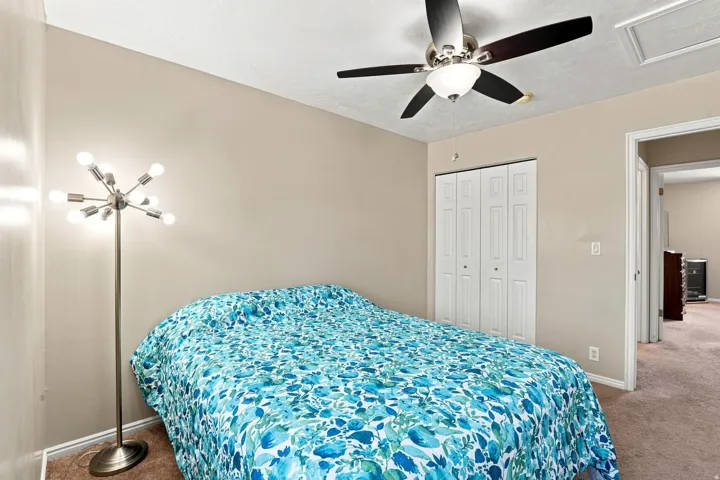 Ceiling fan with integrated lighting, neutral wall tones, carpeted flooring, and bi-fold closet doors