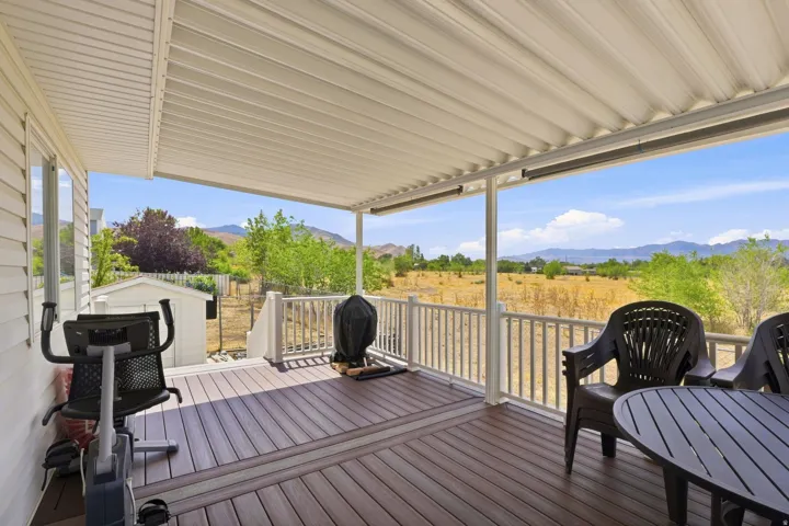 Covered outdoor deck with composite decking, white railing, and panoramic mountain scenery
