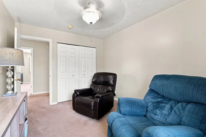 Neutral wall color, carpeted flooring, bi-fold closet doors, and ceiling fan with lighting