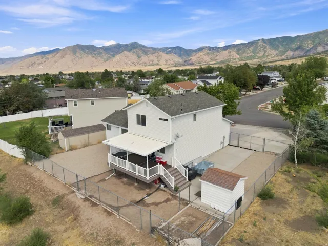 Expansive gravel yard with chain-link fencing, featuring a covered deck and a detached storage shed