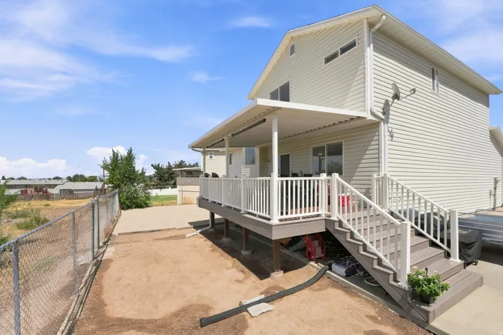 Two-story exterior with horizontal siding, covered deck, composite stairs, and white railings