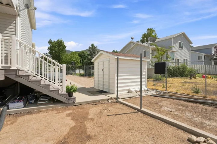 Deck with white railings and composite steps, concrete patio, and storage shed