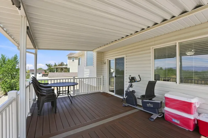 Covered outdoor deck with composite decking, white railing, and sliding glass door access