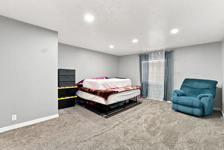 Recessed ceiling lighting illuminates a carpeted interior space with a window featuring blinds and drapes