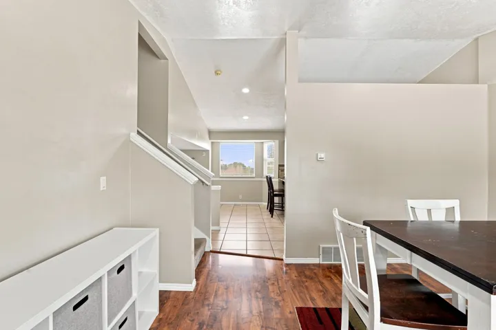 Hardwood-finish flooring, staircase with white railing, recessed lighting, and tile flooring in the adjacent room