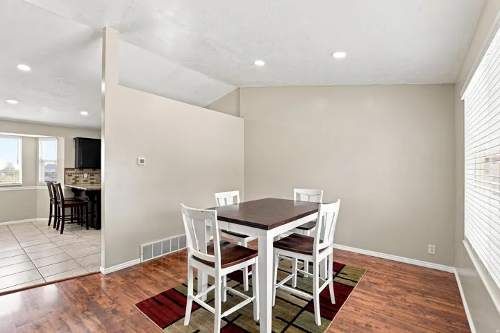 Recessed lighting, wood-finish flooring, half wall partition, window with blinds, and tile flooring in background