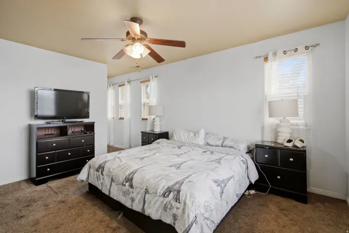 Carpeted room featuring a ceiling fan with integrated lighting and multiple windows