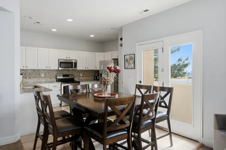 White shaker-style cabinetry with dark hardware, stainless steel appliances, speckled stone countertops, and a full-height mosaic tile backsplash