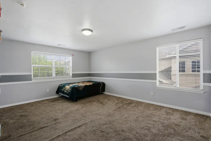 Carpeted room with two windows featuring blinds, a two-tone painted wall, and a flush-mount ceiling light