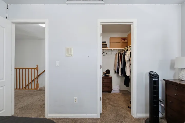 Carpeted flooring, white trim, and a built-in closet with shelving