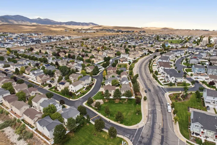 Residential community with varied architectural styles, paved roads, established landscaping, and mountain backdrop