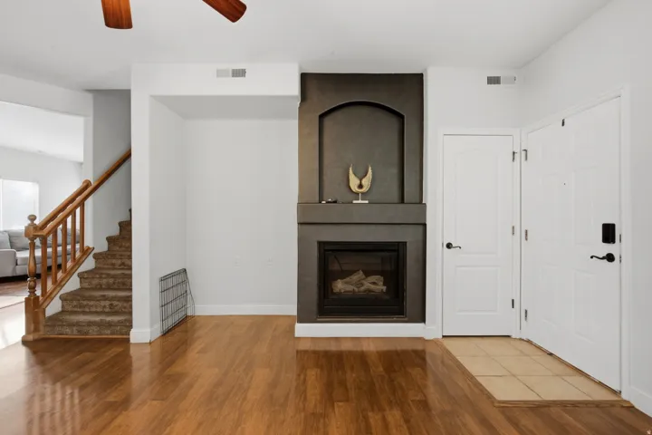 Wood-finish flooring with a tile entry, complemented by a fireplace with a dark surround and an arched niche