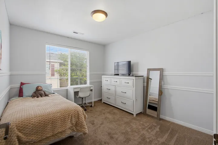 Neutral wall paint, ceiling-mounted light fixture, window with blinds, and carpeted flooring
