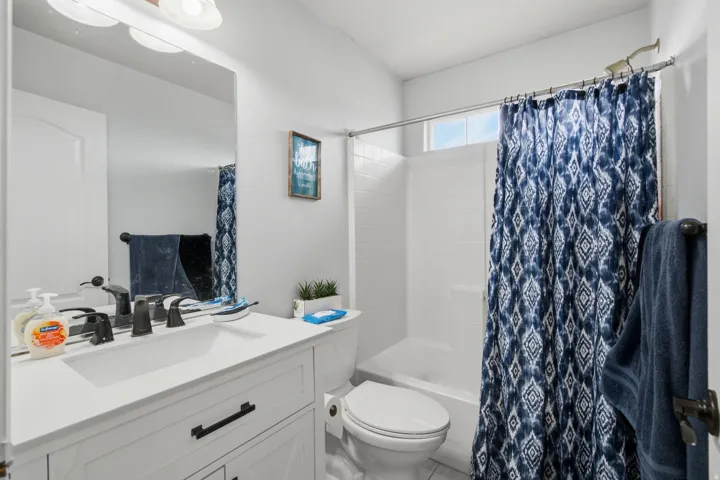 White vanity with a single basin sink and dark hardware