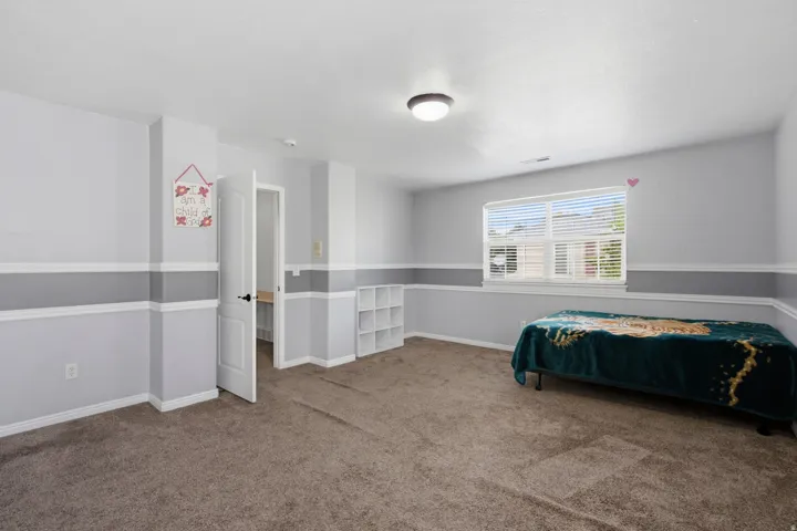 Recessed window with blinds, overhead flush mount light fixture, interior door with black hardware, built-in shelving, and carpeted flooring