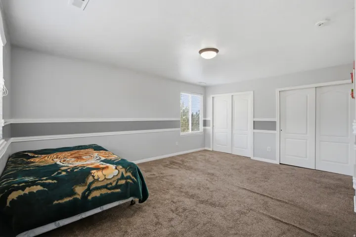 Recessed window with blinds, dual sliding closet doors, and broadloom carpeting
