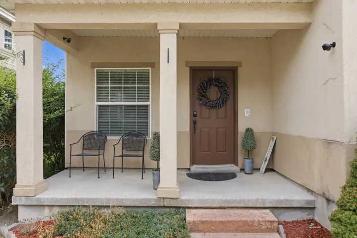 Covered front porch featuring stucco exterior, a paneled entry door, and concrete steps