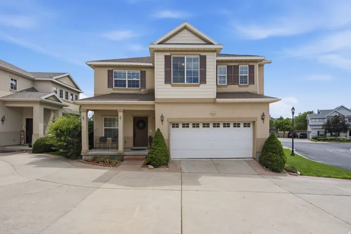 Two-story stucco exterior with a covered porch, a two-car garage, and shuttered windows