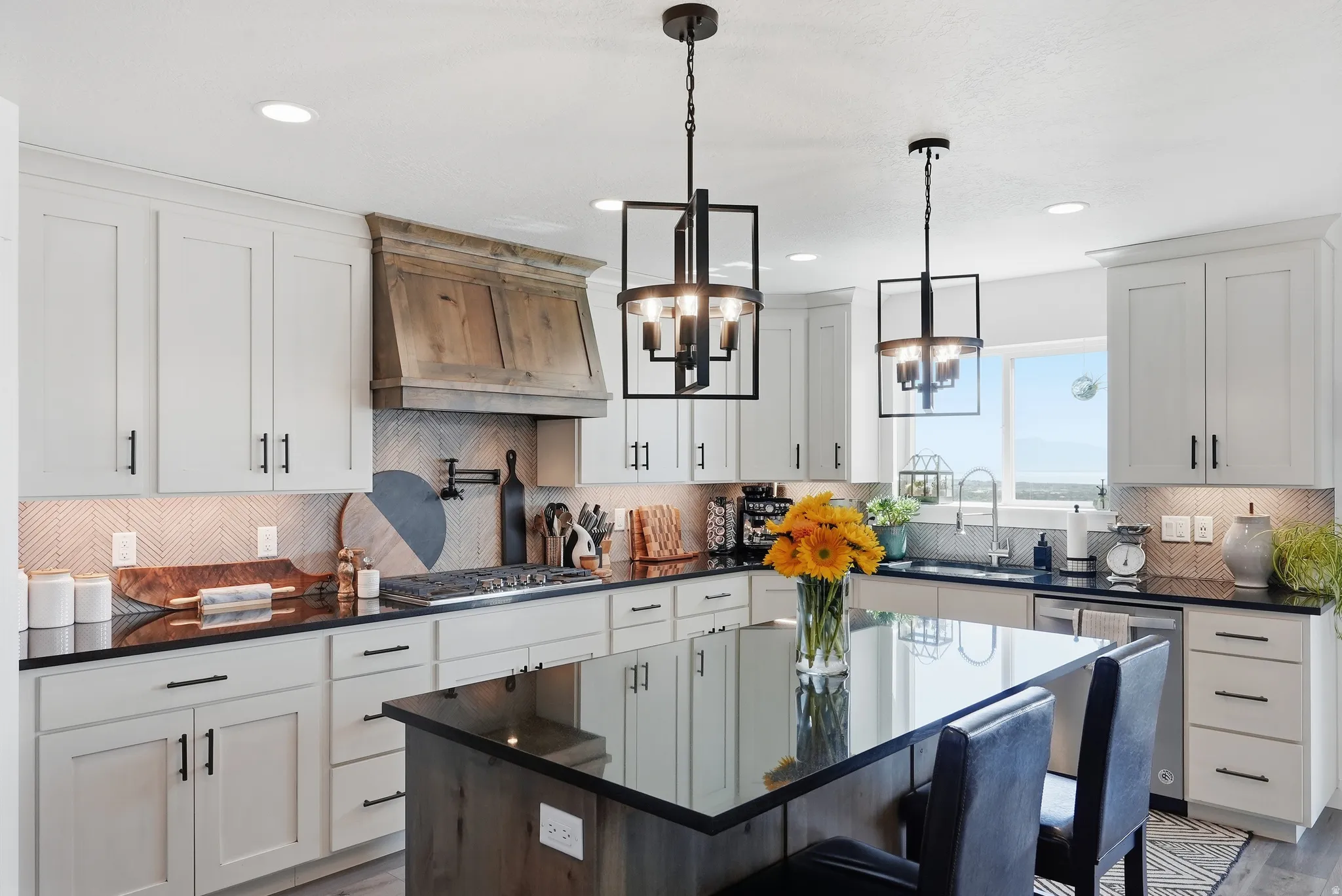 Kitchen featuring white cabinetry, dark countertops, a wood-finish range hood, an island with seating, and pendant lighting