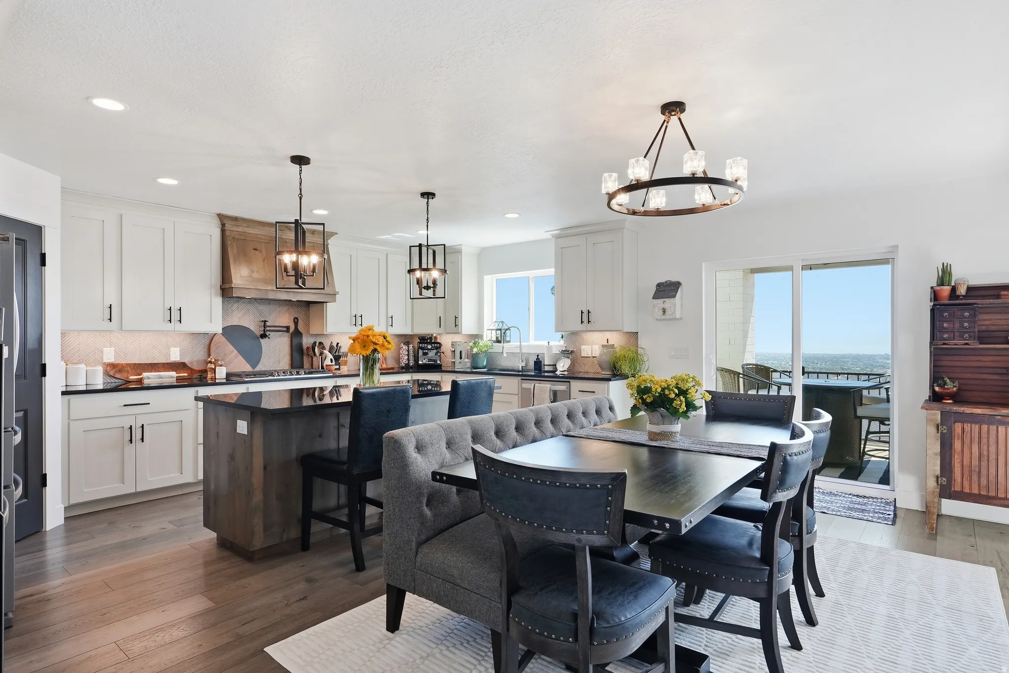 Gourmet kitchen with white cabinetry, wood-finish flooring, and black countertops