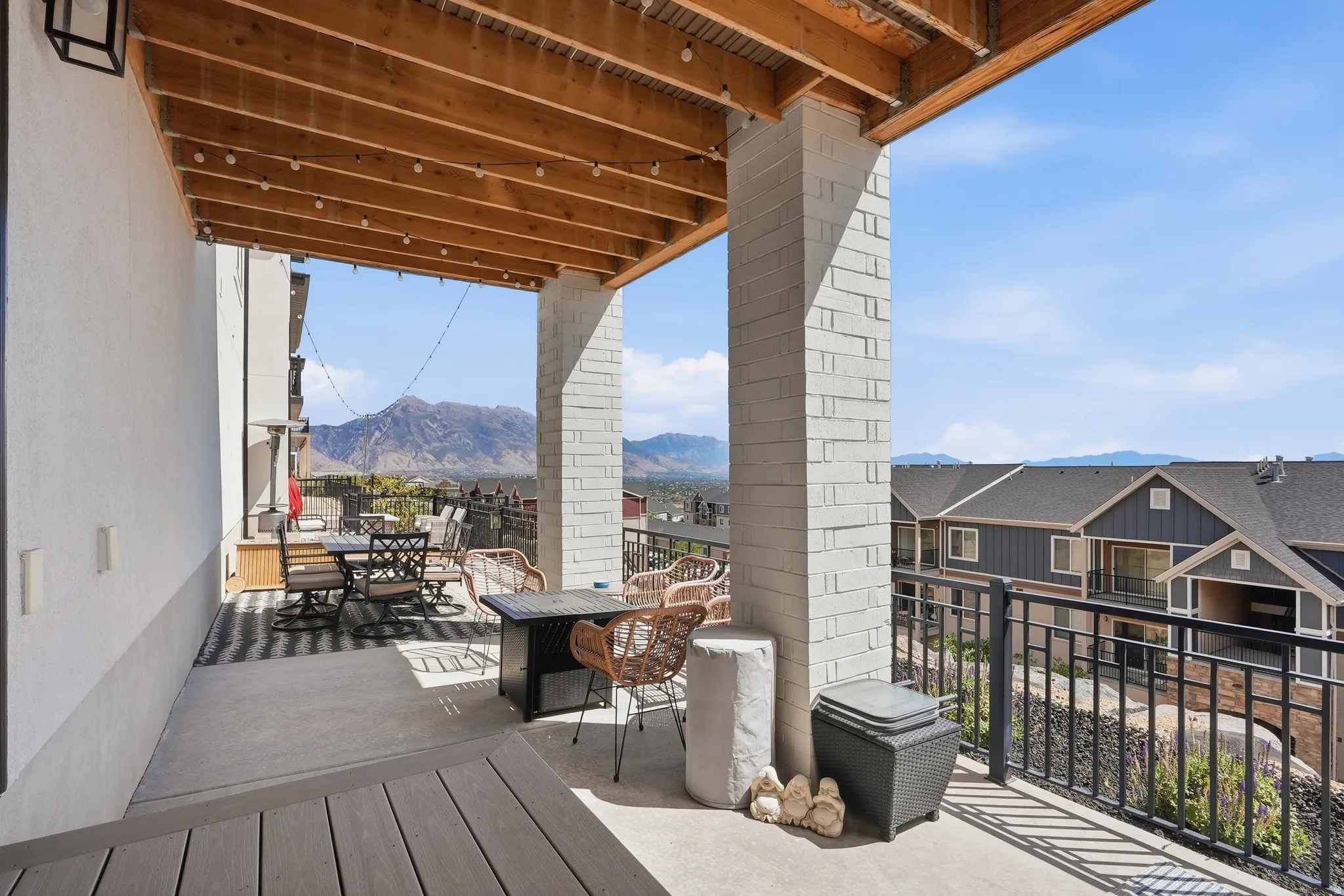 Covered patio featuring a wood-beam ceiling, light brick pillars, and a black wrought iron railing