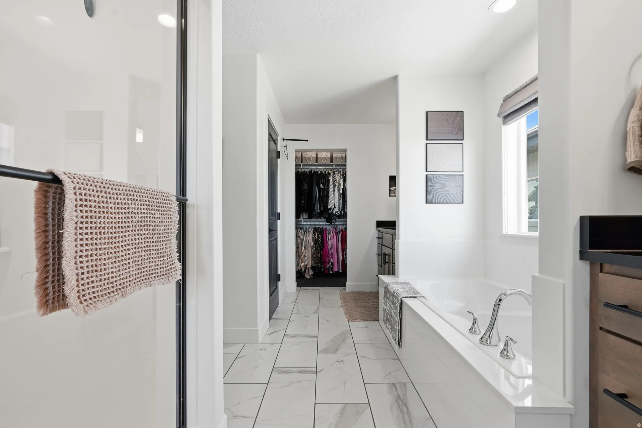 Spacious bathroom featuring a built-in bathtub with polished chrome fixtures, a walk-in shower with clear glass enclosure, and white tile flooring