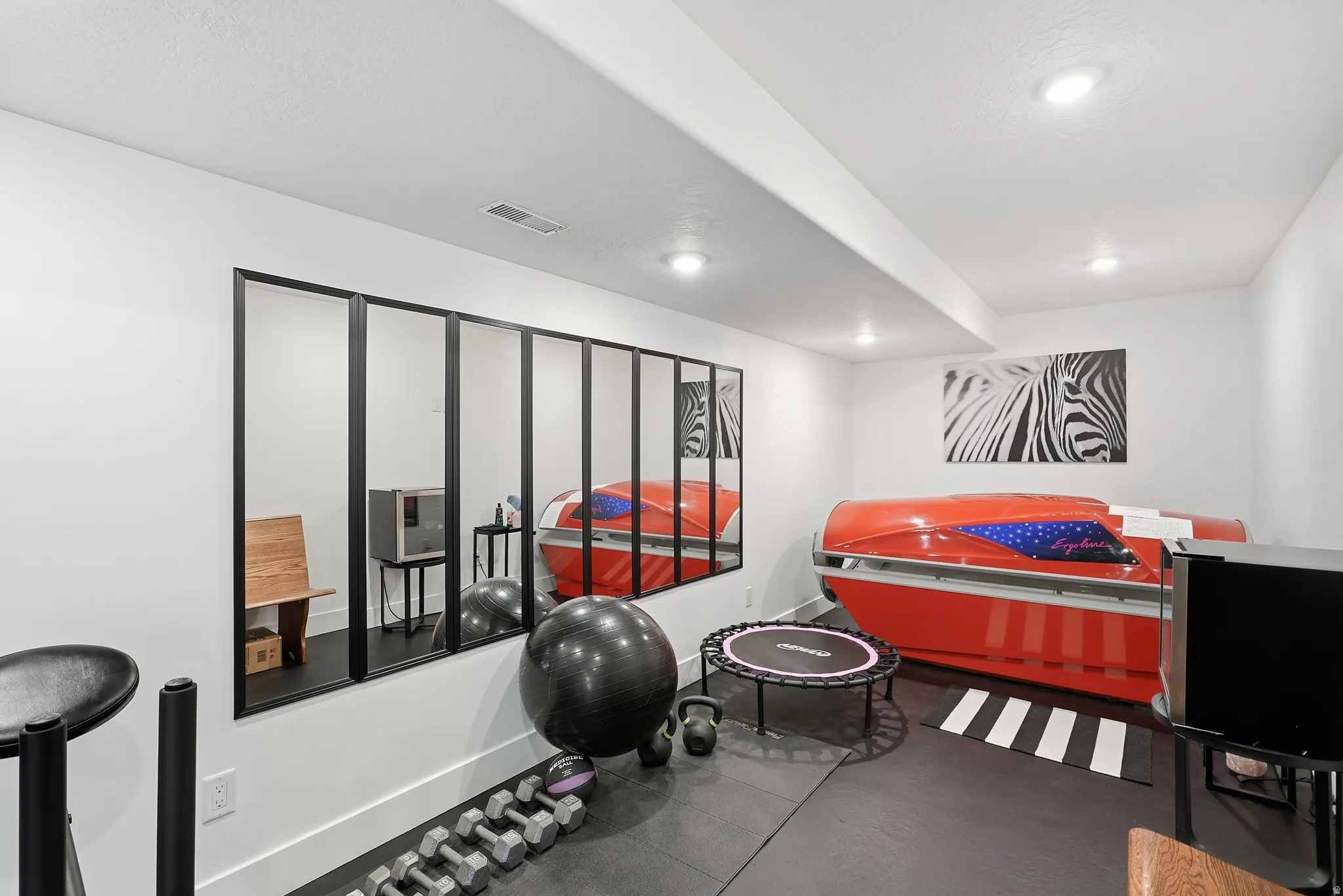 White walls with recessed lighting, large paneled wall mirrors, and durable rubber flooring