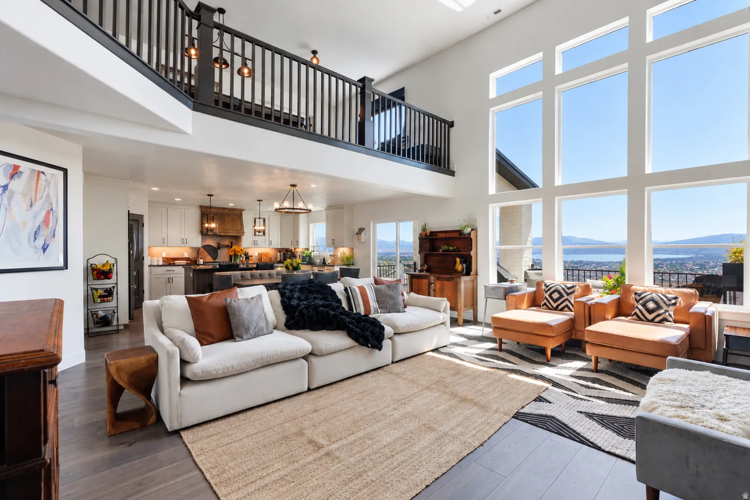 Spacious living area featuring high ceilings, wood-finish flooring, and a second-story balcony with dark wood railings