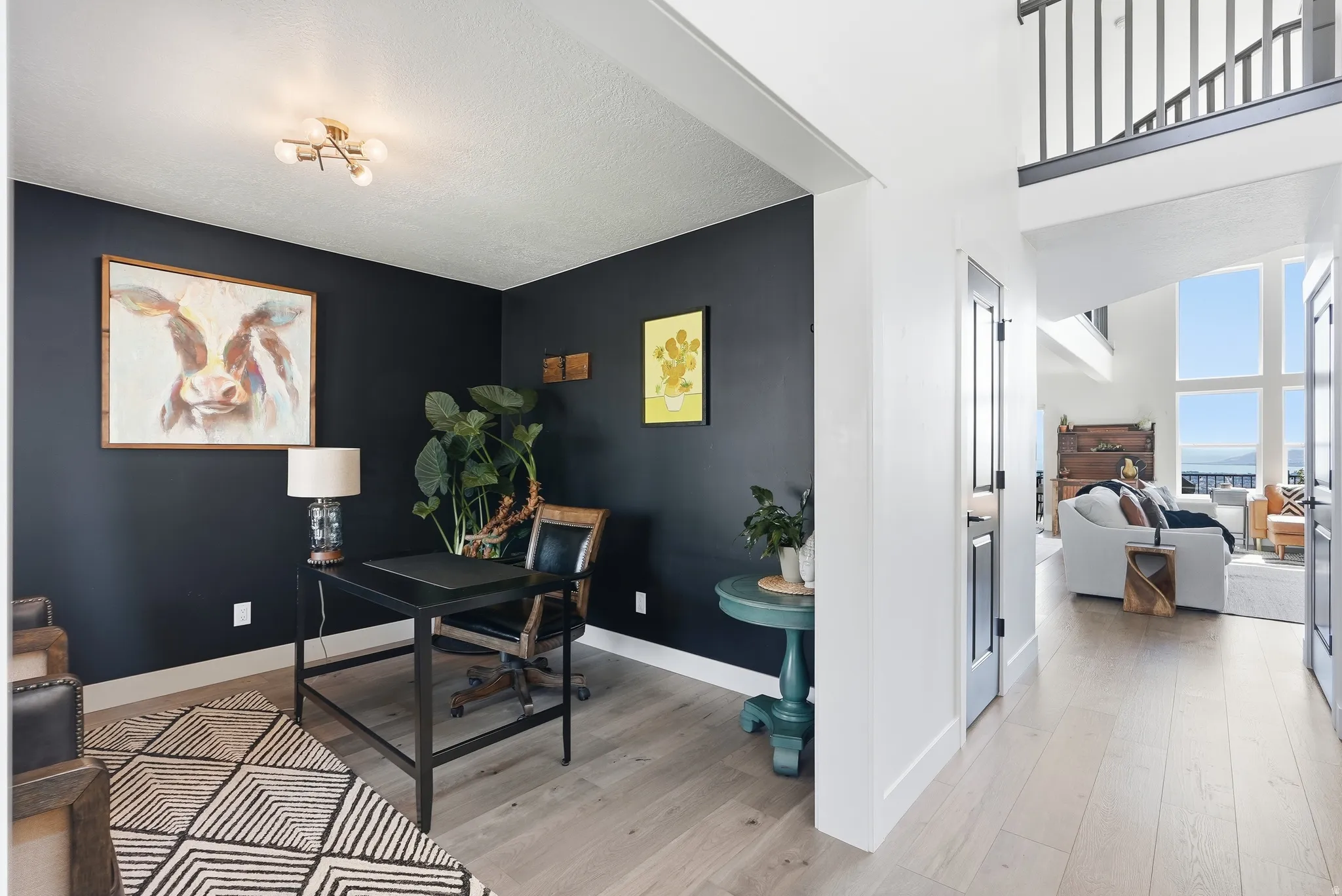 Recessed office space with dark accent wall, light wood-finish flooring, and a contemporary ceiling light fixture