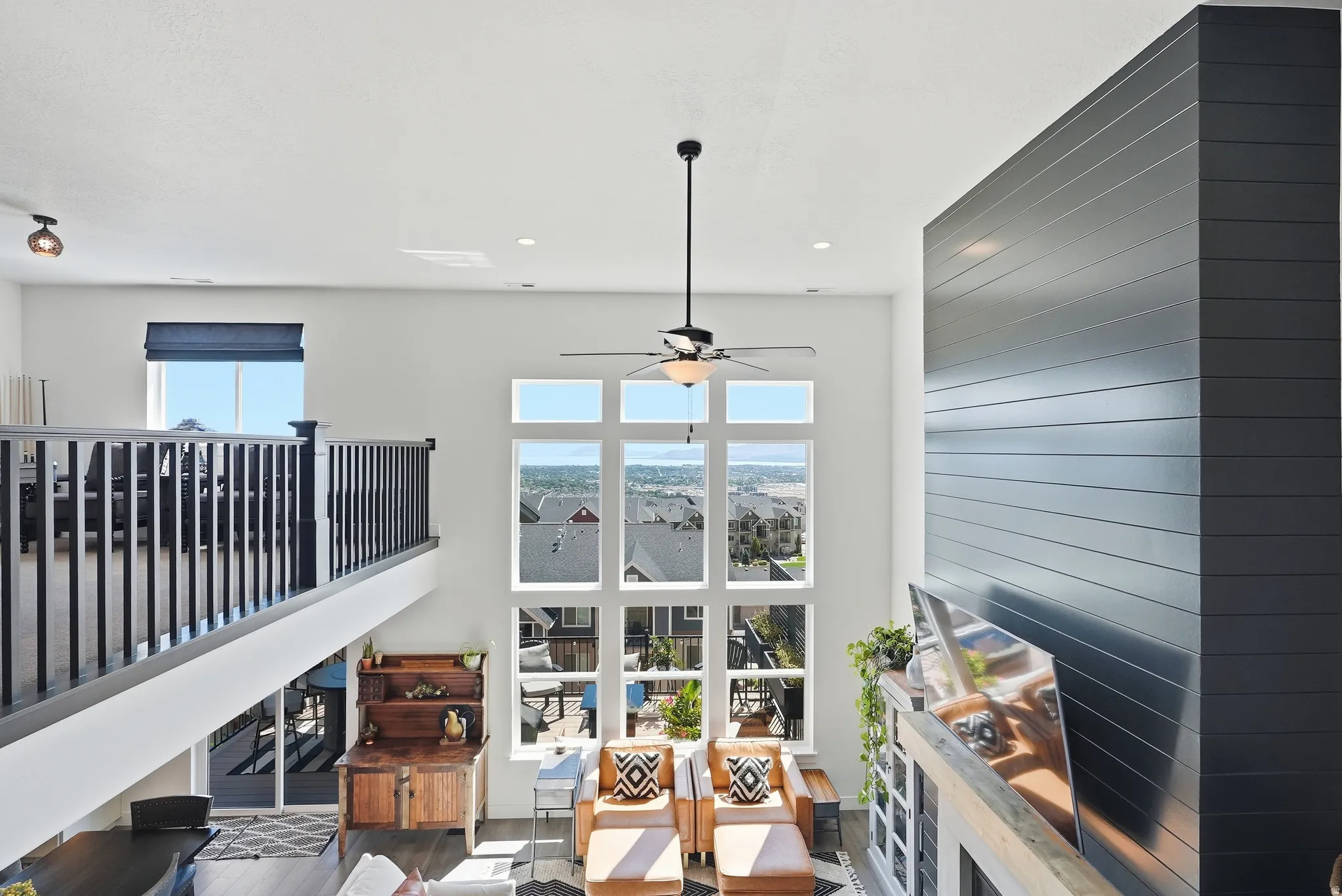 Soaring two-story interior bathed in natural light through expansive multi-pane glass doors and windows overlooking expansive vistas