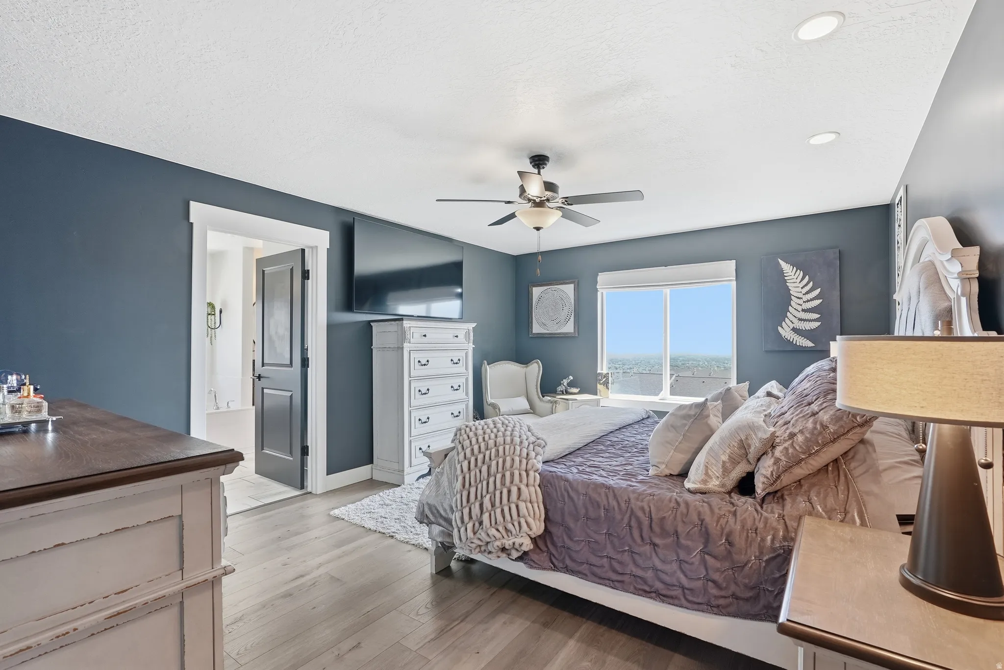 Wood-finish flooring, recessed lighting, ceiling fan, and a large window