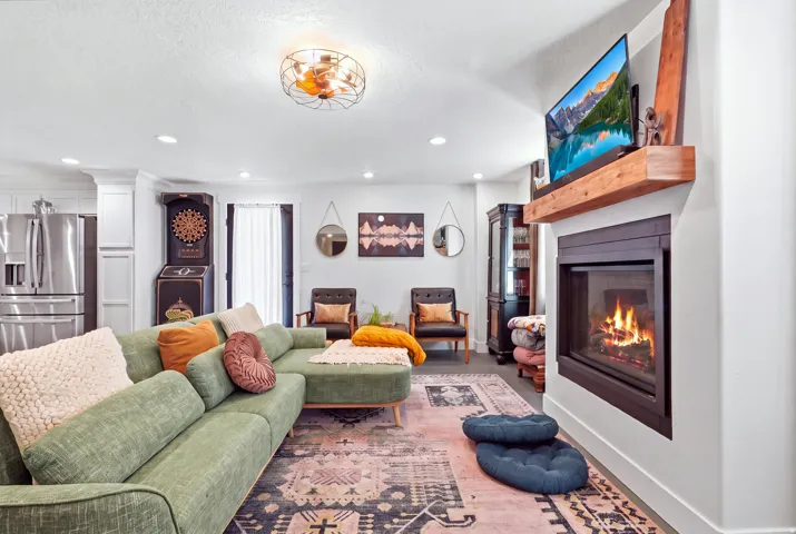 Built-in fireplace with a wood-finish mantel, stainless steel refrigerator, white cabinetry, and recessed lighting