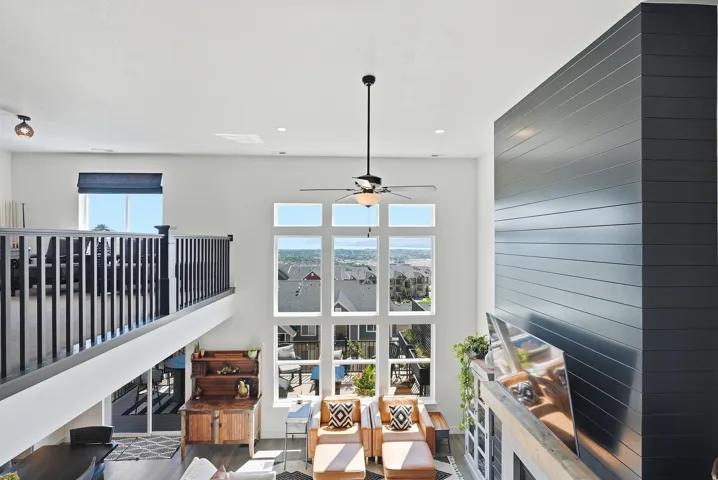 Soaring two-story interior bathed in natural light through expansive multi-pane glass doors and windows overlooking expansive vistas