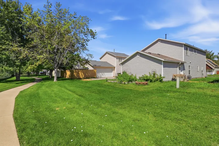 Expansive lawn with mature trees, paved pathway, and privacy fencing