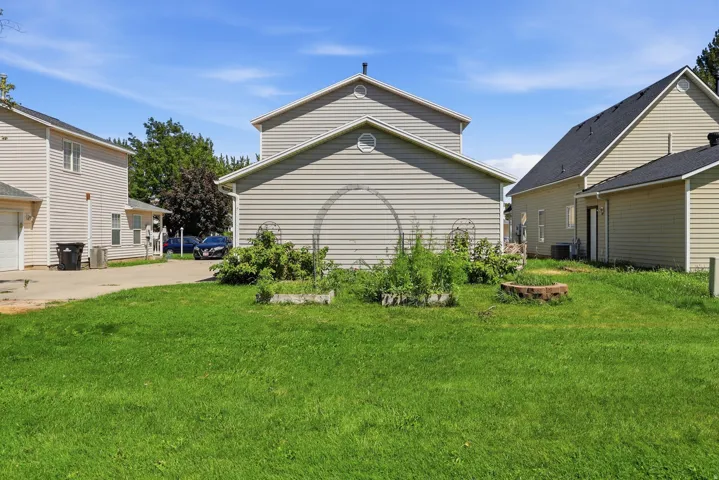 Expansive green space with an established raised garden bed and a brick-lined fire pit
