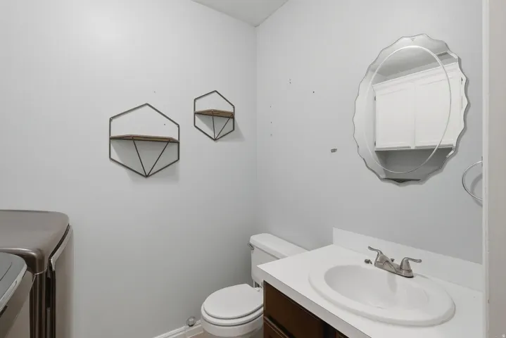 White countertop with an integrated sink and brushed nickel faucet, a dark wood-finish vanity, and a decorative wall mirror