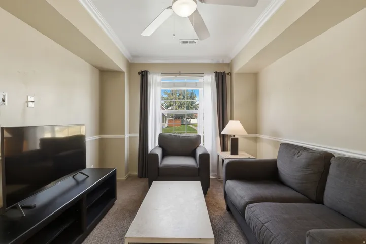 Recessed lighting with a ceiling fan, crown molding, chair rail molding, and a window with exterior views