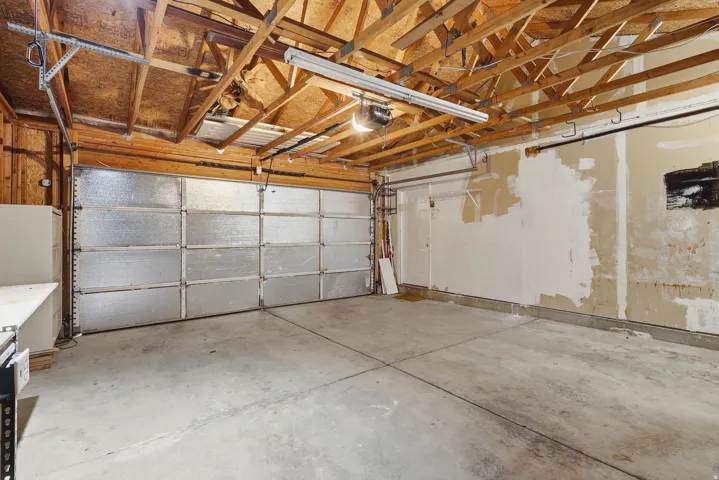 Exposed wood beam ceiling in garage with concrete flooring and a paneled garage door