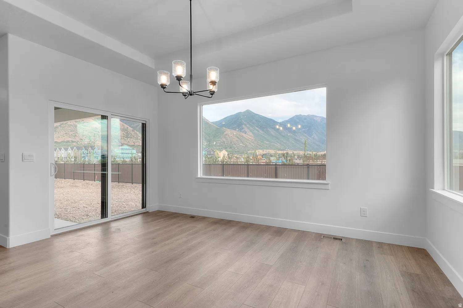 Recessed ceiling details, wood-finish flooring, contemporary chandelier, expansive window, and sliding glass door